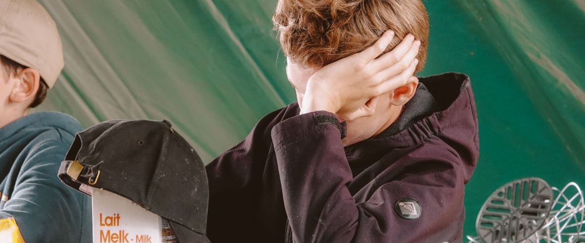 Jongen zit aan tafel op kamp met hand tegen het hoofd