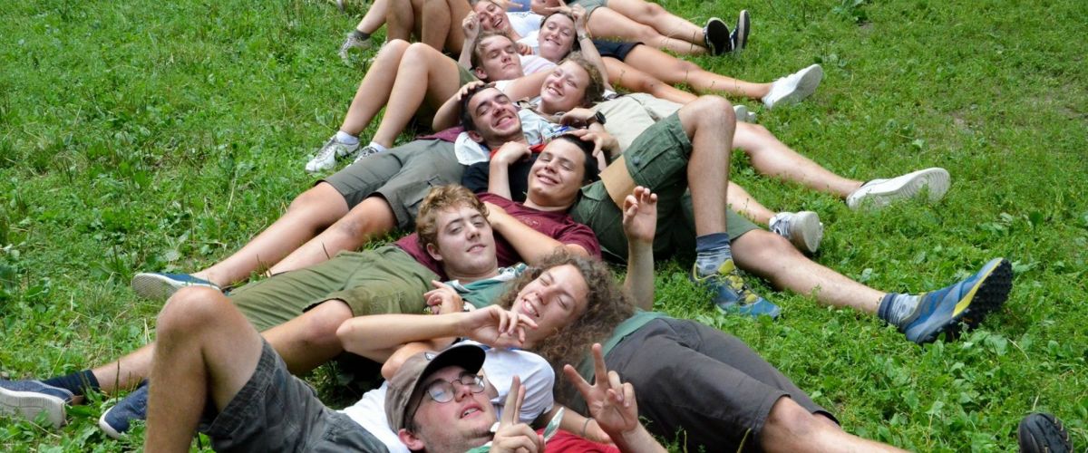 Scoutsleden liggend in het gras, hoofd op elkaars buik.
