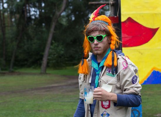 Scoutsleider in uniform met drankje in zijn hand.