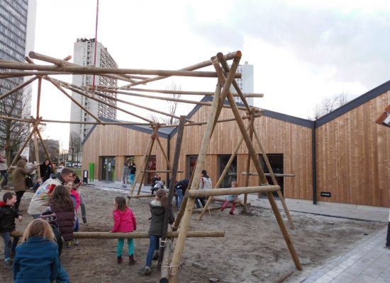 Kinderen die samen met scoutsleiders een grote constructie aan het sjorren zijn.