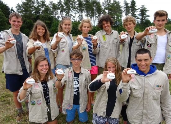 een groep givers die elk een steen vasthouden waar hun voortotem opstaat