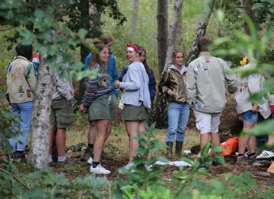 Groepje leiding staan in een kring in het bos op Herfstontmoeting