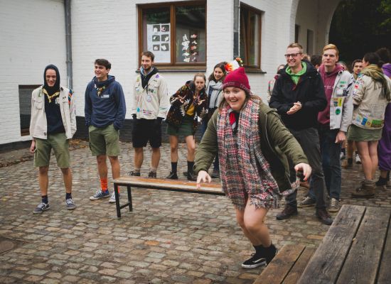 Scoutsleiding staan in twee groepjes op de binnenplaats van De Kluis. Klaar voor een spel. Van een groep begint iemand te lopen.