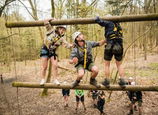 Drie leiders zijn beveiligd en helpen elkaar op het touwenparcour op Jeugdverblijf De Kluis.