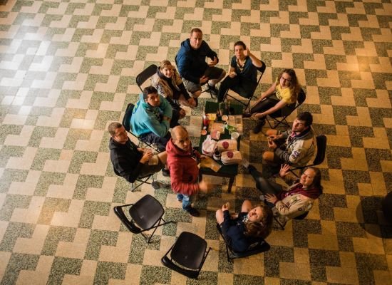 Groepje leiding zit samen rond de tafel, ergens onderweg.