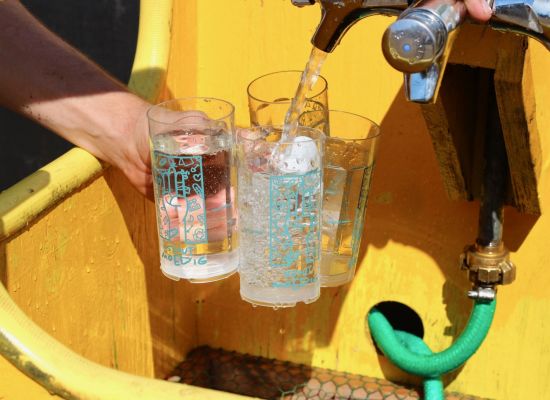 Drie Herfstontmoetingsbekers worden aan een kraantje gevuld met water.