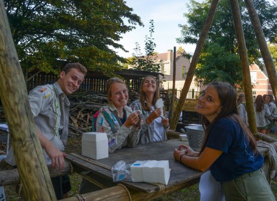 scouts en gidsen aan een gesjorde eettafel.