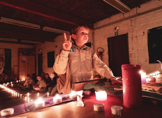 Een welp legt zijn belofte af. Een hand in welpengroet het andere hand op de scoutsvlag.