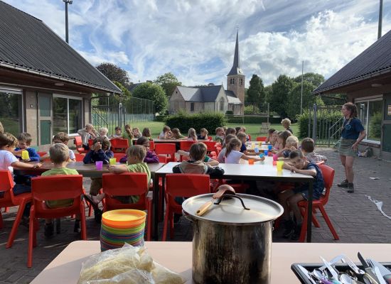 Leden aan tafel op hun zomerkamp