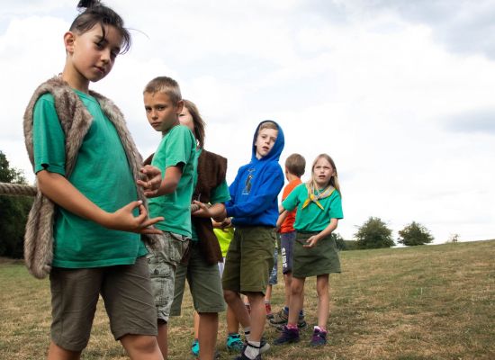 jonge scouts en gidsen in een rijtje achter elkaar, klaar om te beginnen touwtrekken.