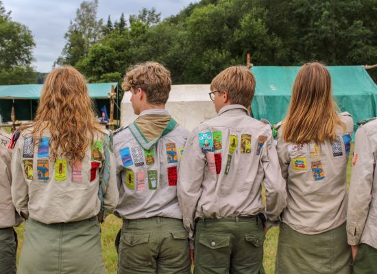 4 givers, rachterzijde scoutshemden met veel jaarkentekens