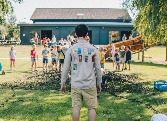 Leider staat voor een groep leden op het scoutsterrein