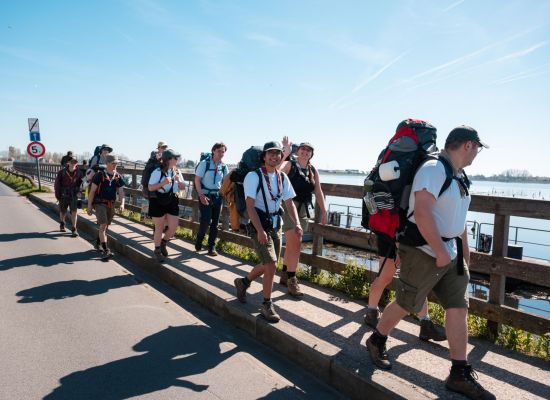 Groepje leiding wandelt langs het water op Gilwell Onderweg