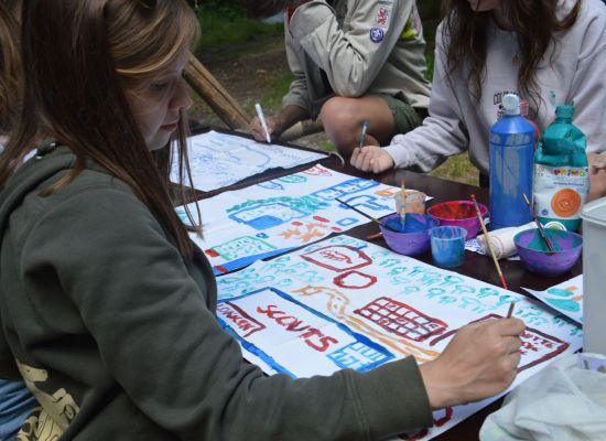 Een meisje schildert een scoutslokaal