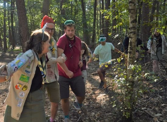 Scoutsleden doen een spel in het bos