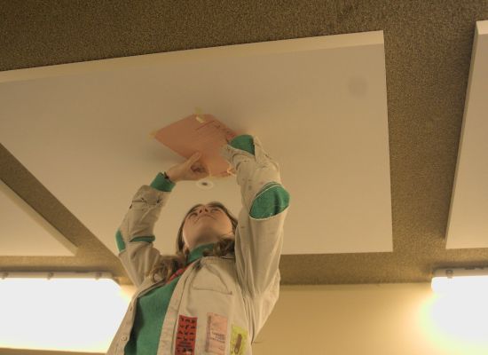 Leiding schrijft op een papier tegen het plafond.