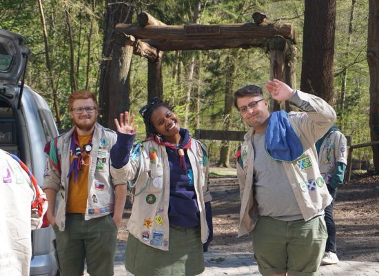 Structuurvrijwilligers zwaaien naar de camera in het bos van de Kluis