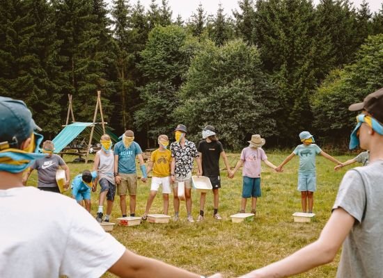 Jonggivers in een kring met blinddoek op op kamp