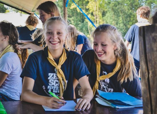 Twee zeeverkenners vullen papieren in