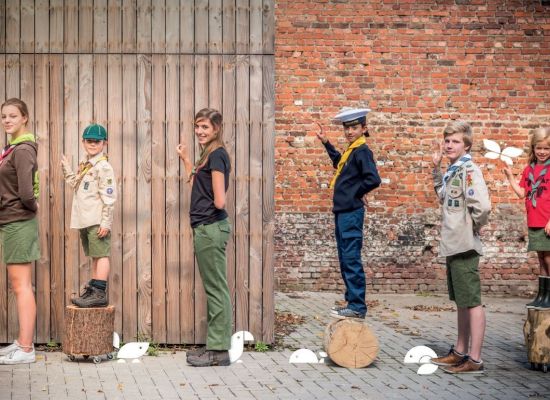 scouts en gidsen poserend in allerlei vormen van het scoutsuniform 