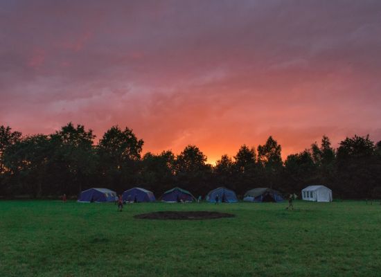 tenten aan de bosrand onder een ondergaande zon