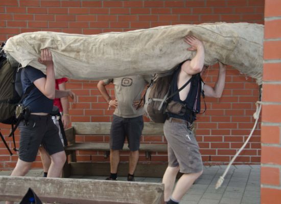 2 mensen dragen een grote opgerolde tent