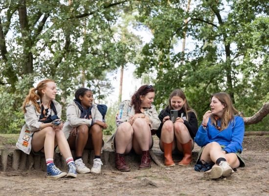 vijf leidsters zittend op een balk