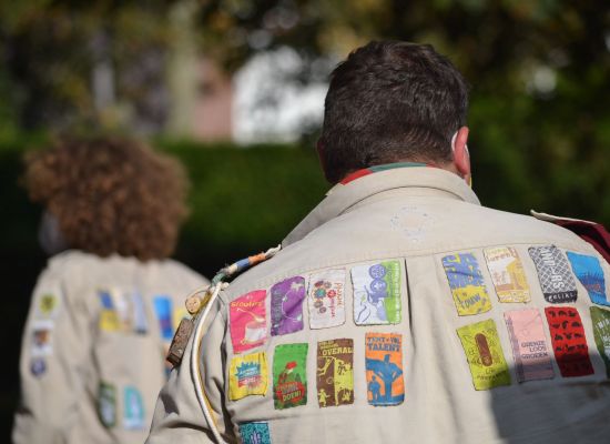 Leider heeft uniformhemd aan. Op het hemd is een hele verzameling jaarkentekens genaaid.