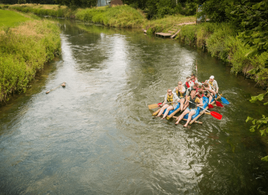 Scouts varen met een zelfgemaakt vlot op de rivier.
