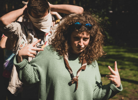 Coole leidster met zonnebril in de haren doet het V-teken met haar handen.