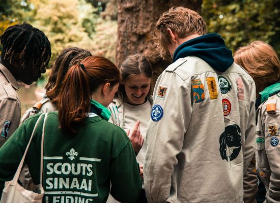 leden en leiding staan in een kringetje voorovergebogen