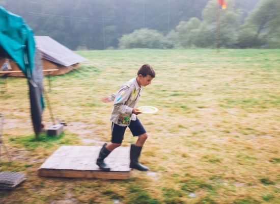 Jonggiver die door de regen naar de tent loopt