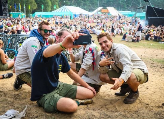 Leiders nemen een selfie, op de achtergrond is herfstontmoeting aan de gang.