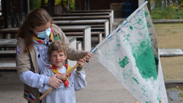 Leidster met mondmasker en lid zwaaien met een zelfgeschilderde vlag