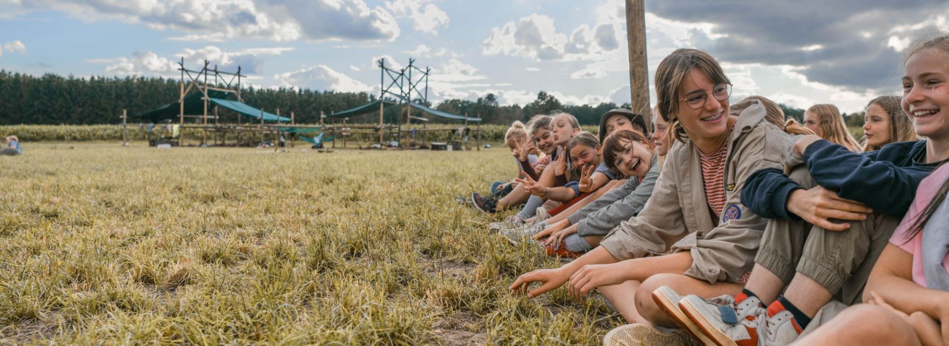 scouts zittend langs een veld